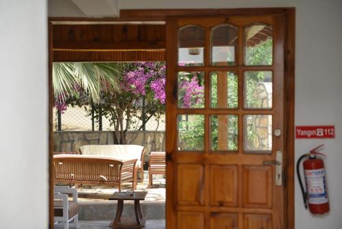 an open door to a patio with a bench and flowers at Double Comfort Otel in Muğla