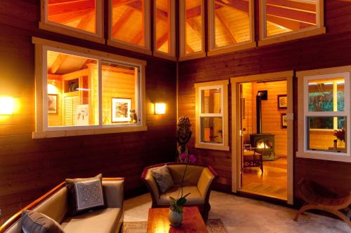 a living room with a couch and chairs and windows at Volcano Mist Cottage in Volcano