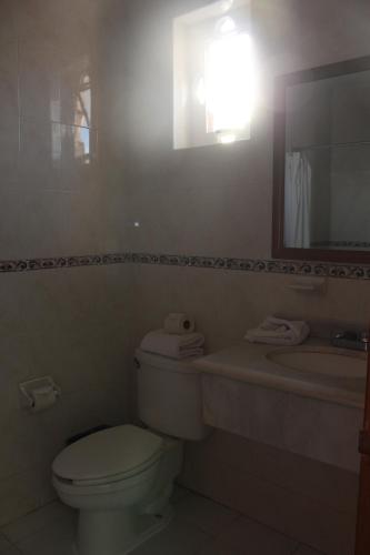 W łazience znajduje się toaleta, umywalka i lustro. w obiekcie Vista Express Morelia by Arriva Hospitality Group w mieście Morelia