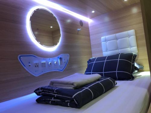 a bedroom with a bed with a mirror and pillows at CapsulePod@Aljunied in Singapore