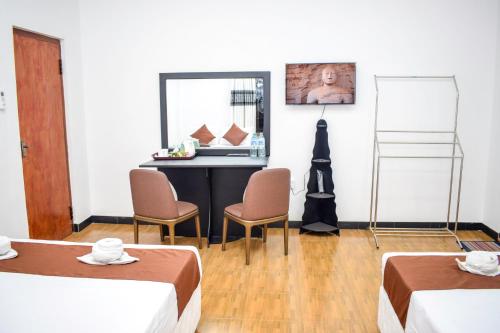 a room with two beds and a table and a mirror at Lion Resort in Polonnaruwa