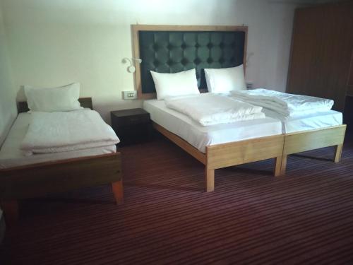 a bedroom with two beds with white sheets at Hotel Rezang-La in Leh