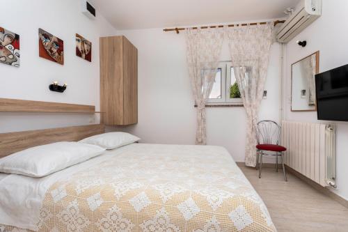 a bedroom with a bed and a tv and a window at Apartments Hana in Baška