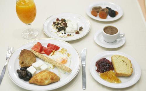 a table with plates of breakfast foods and a drink at Hotel Metropol in Larisa