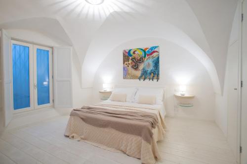 Cette chambre blanche dispose d'un lit et d'une peinture murale. dans l'établissement La Finestra sul Convitto B&B, à Lecce