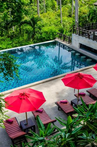a swimming pool with red umbrellas and chairs next to it at Kirikayan Residences Koh Samui in Mae Nam