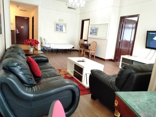 a living room with black leather furniture and a tv at Grand Service Apartment @ Times Square in Kuala Lumpur