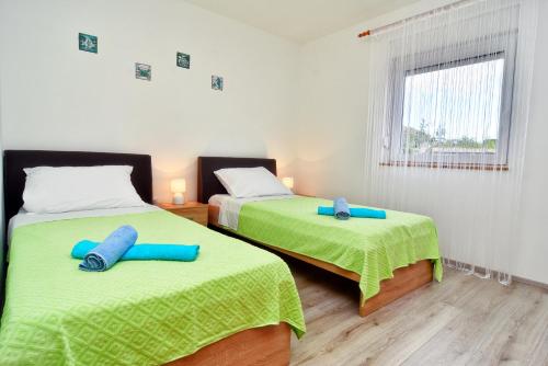 a bedroom with two beds with green sheets at Kuća za odmor Diana in Sukošan