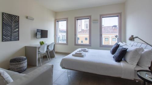 een witte slaapkamer met een bed en een bank bij Erïk Langer Pedrocchi Suites in Padua