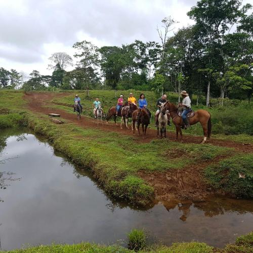 a group of people riding horses down a dirt road at Hotel SueñoReal RioCeleste in Rio Celeste