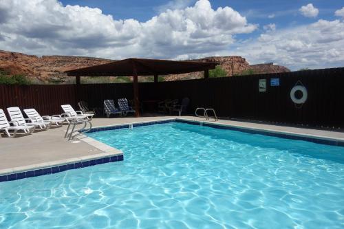 a swimming pool with chairs and a gazebo at Golf course condo in Moab in Moab