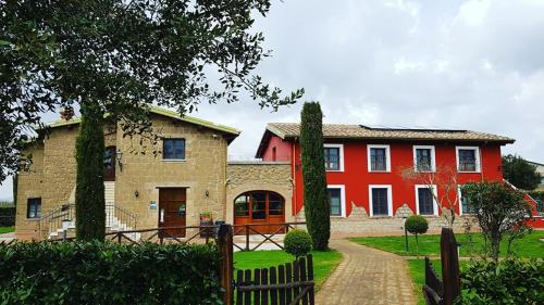 a red house with a fence in front of it at Agriturismo Podere Del Lepre in San Quirico
