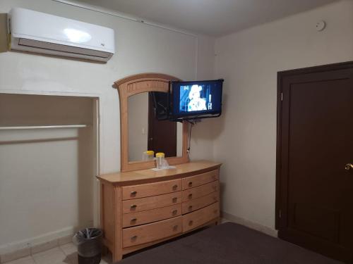 a bathroom with a television and a dresser with a mirror at HOTEL BAEZA in Delicias