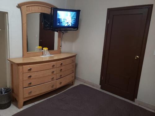 a bathroom with a dresser with a mirror and a television at HOTEL BAEZA in Delicias