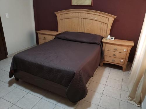 a bedroom with a bed with a wooden headboard and a night stand at HOTEL BAEZA in Delicias
