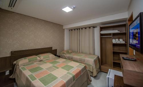 a hotel room with two beds and a television at Tambau Beach Hotel in João Pessoa