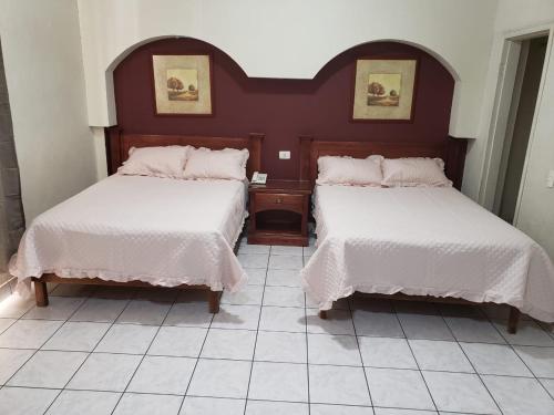 a bedroom with two beds with white linens at HOTEL BAEZA in Delicias
