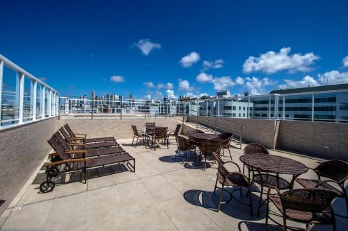 a patio with tables and chairs on a balcony at Tambau Beach Hotel in João Pessoa