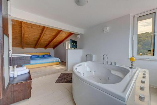 a large white bath tub in a room with a bed at Apartments Savar - Ilo in Brbinj