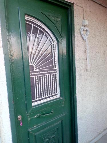 a green door with a heart on a wall at Cozy house 3 in Vrahati