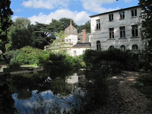 an old building with a reflection in a pond at Haus Annaberg in Bonn