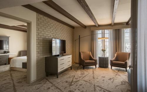 a bedroom with a bed and two chairs and a television at Casa De Palmas, Trademark Collection by Wyndham in McAllen