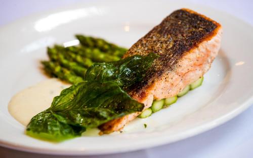 a white plate with a piece of salmon and greens at Casa De Palmas, Trademark Collection by Wyndham in McAllen