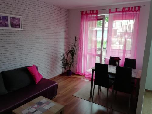 uma sala de estar com um sofá, uma mesa e cor-de-rosa cortinas em Apartament u Magdy em Międzyzdroje