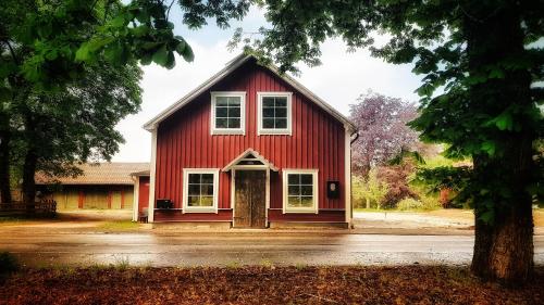 a red barn with white windows and a door at Lundsbrunn B&B in Lundsbrunn