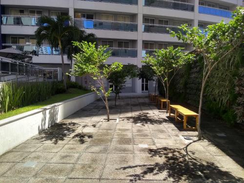 a walkway in front of a building with trees and benches at Apartamento 2 quartos May Way Meireles uma quadra da Beira-mar in Fortaleza