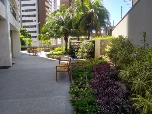 a patio with a chair and some plants and trees at Apartamento 2 quartos May Way Meireles uma quadra da Beira-mar in Fortaleza