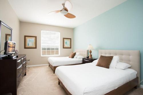 a bedroom with two beds and a flat screen tv at Shoreway Condo #231522 in Orlando