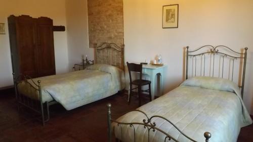 a bedroom with two beds and a table with a chair at Corte Ramedello in Cerea