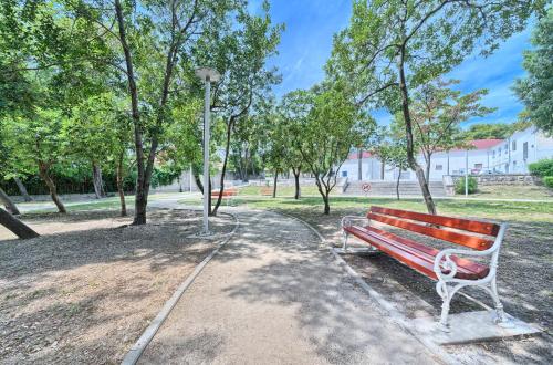 a bench in a park with trees and a street light at Apartments Meštrović with heated swiming pool- near Split in Kaštela