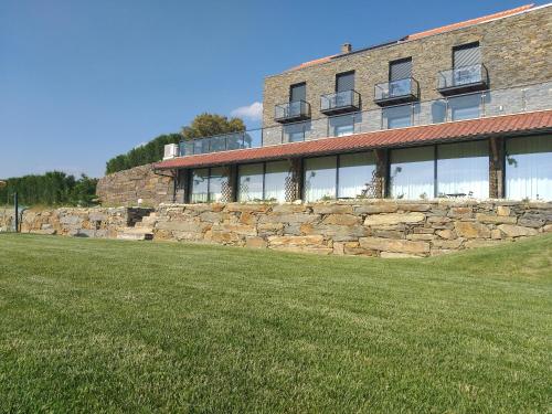 a building with a stone wall and a grass field at Quinta da Corujeira in Vila Real