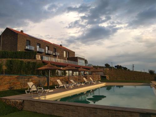 una piscina con sillas y sombrillas junto a un edificio en Quinta da Corujeira, en Vila Real