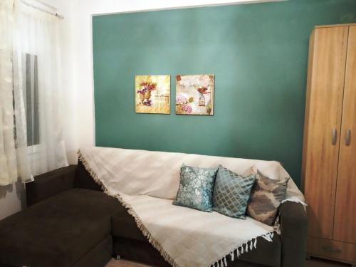 イラクリトサにあるSweet Home Nea Iraklitsaの壁に絵画が2点飾られた部屋のソファ