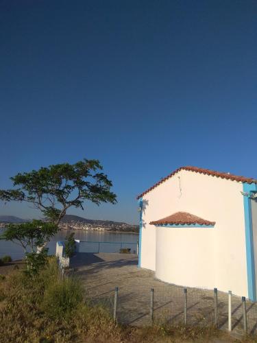 a white building with a tree next to a body of water at DREAM & HARMONY in Artemida