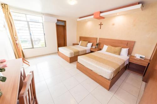 a hotel room with two beds and a cross on the wall at Hotel Elizabeth Central in Aguascalientes