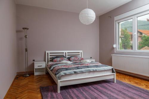 a white bedroom with a bed and a window at Apartment Mihajlovic in Vranje