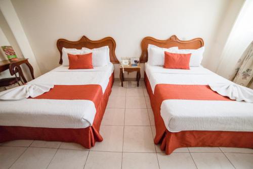 a hotel room with two beds with red and white sheets at Hotel Elizabeth Central in Aguascalientes