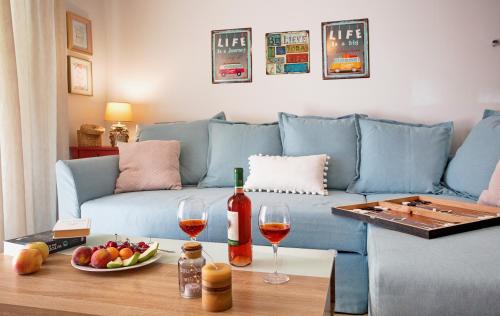 ネア・ペラモスにあるMyrsini's Apartmentのリビングルーム(青いソファ、ワイングラス付きのテーブル付)