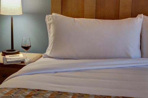 a bed with a white pillow and a glass of wine at The Glen House in Gorham