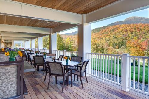 a deck with tables and chairs and a view of the mountains at The Glen House in Gorham
