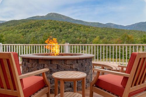 a fire pit on a deck with chairs and mountains at The Glen House in Gorham