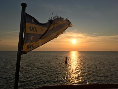 a flag on a boat in the ocean at sunset at Noorderzon in Buren
