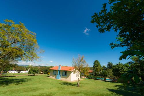 a house with a red roof on a green field at Hotel Alto da Boa Vista in Analândia