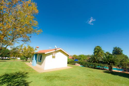 a small white house in a field of grass at Hotel Alto da Boa Vista in Analândia