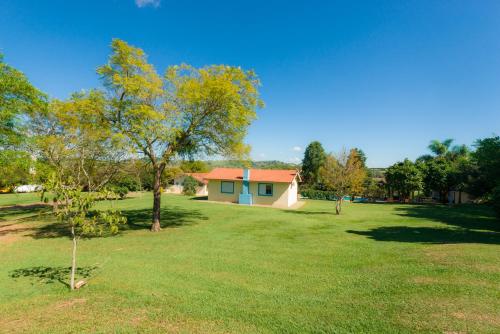 a house in a grassy yard with a tree at Hotel Alto da Boa Vista in Analândia