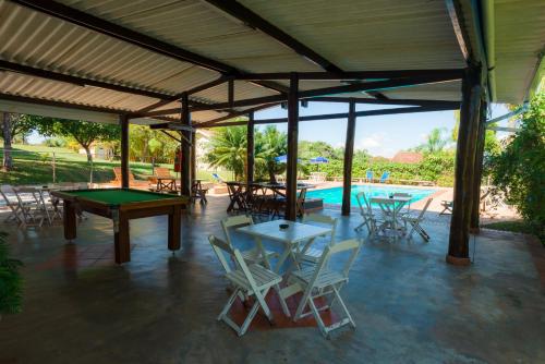 a covered patio with tables and chairs and a pool at Hotel Alto da Boa Vista in Analândia
